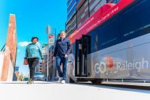 Two riders walking away from the bus in Downtown Raleigh