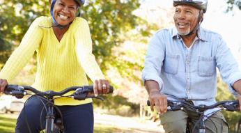 Older couple riding bicycles wearing helmets
