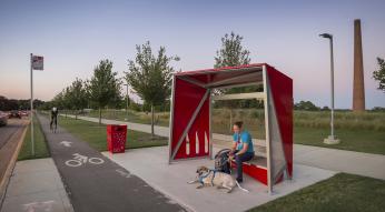 Man with dog waiting at red bus shelter at the museum