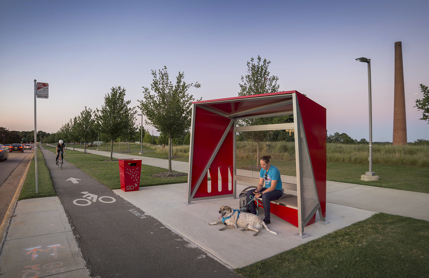 Man with dog waiting at red bus shelter at the museum